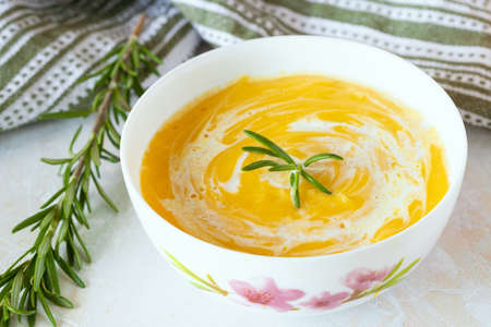 pumpkin soup with cream in a white plate and rosemaryの写真素材
