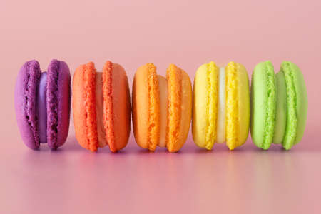 multicolored macaroons in a row on a pink background; macaroons in red, orange, purple, yellow and green colorsの写真素材