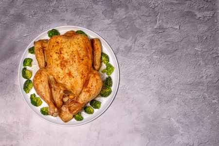 baked whole chicken with broccoli on a round dish