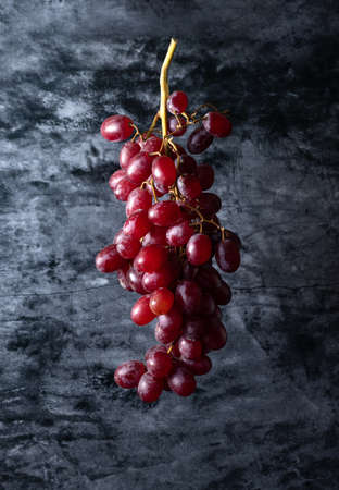 a bunch of red grapes hangs in the airの写真素材