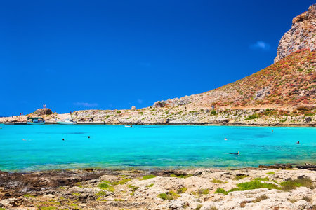 2019, JUNE, THE 4TH: - GREECE, THE CRETE ISLAND, BALOS - The castle on the top of the mountain and the people on the beach below it.のeditorial素材