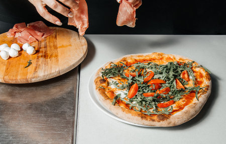 Cooking process of traditional italian pizza with ham, cheese, mozzarella on a table, restaurant kitchen conceptの写真素材