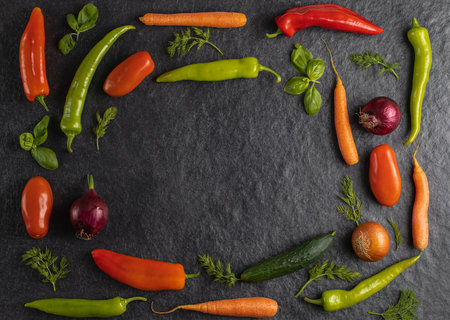 Fresh seasonal vegetables: green pepper, tomato, onion, carrot, cucumber, basil, dill on grey black background, space for text, top view, stock photoの写真素材
