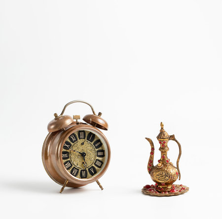 Old vintage alarm clock and small jug with stones on a white background, space for text