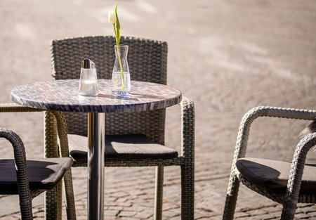 Empty tables outside between lunch hours along a cobblestone alley in a European city, a veranda, a cafeの写真素材