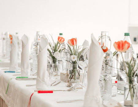Festive decorated table in a restaurant, wine glasses, vase, flowers, mineral water bottles,...