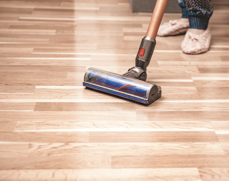 Woman cleaning floor using vacuum cleaner at home, house work, closeupの写真素材