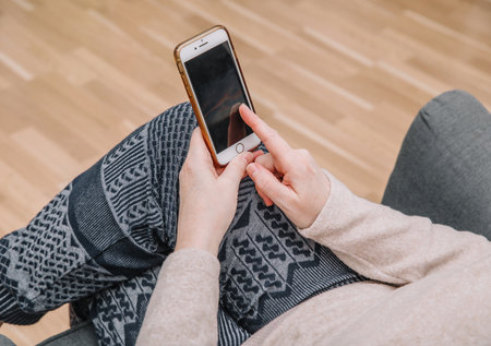 An elderly woman holds and uses a smartphone in her hand, a smartphone. Grandmother hands. Closeup, the concept of family connectionsの写真素材