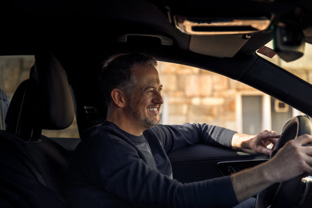 Happy smiling attractive businessman in a casual cloth driving a car in the city, test drive