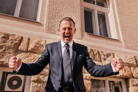 Business man in front of the office building, happy emotions, the end of the work day, the last day before vacationの写真素材