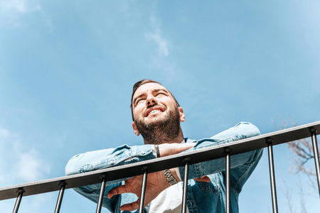 Portrait of a handsome hipster smiling man in a jean jacket. A man in a big city on the street, a life style conceptの写真素材