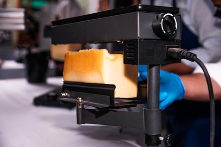 Melting and slicing raclette cheese using an electric melterの写真素材