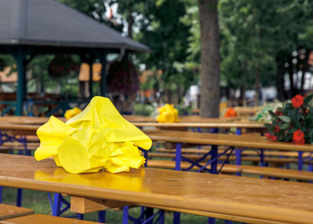 Yellow folded umbrella on wooden picnic bench in public park, outdoor seating, picnic area conceptの写真素材