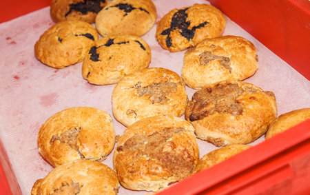 Golden brown cookies with chocolate chips and nuts, freshly baked on red tray, homemade pastries,...