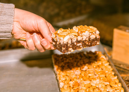 Hand grasping a tasty homemade nut bar, nutritious snack created at home, ideal for maintaining...