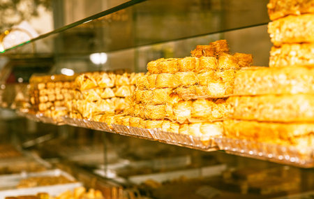 Traditional Middle Eastern desserts stacked in bakery display, sweets, pastries, confectionery, cultural dishes, food photography conceptの写真素材