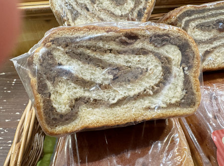 Rustic marble rye bread with swirled pattern wrapped in plastic on display.