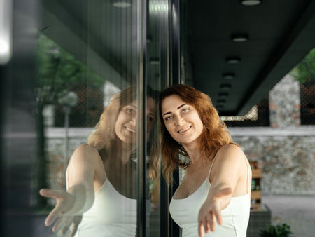 Portrait of a smiling young woman standing in front of a window.の写真素材