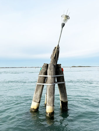 Wooden navigation buoy in calm ocean waters under clear sky.の写真素材