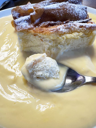 Creamy vanilla custard with flaky apple strudel on a white plate.の写真素材