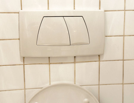 Dual flush toilet buttons on tiled wall for water efficiency.の写真素材