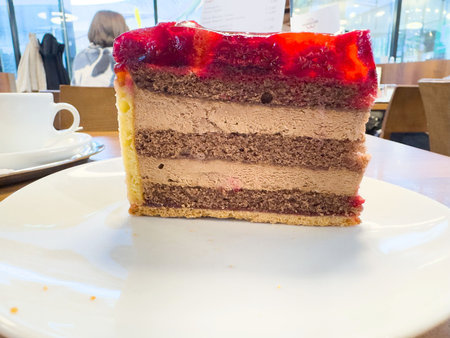 Delicious chocolate layer cake slice with berry topping in cafe setting.