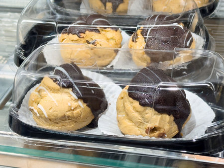 Tempting cookie dough treats with chocolate coating are showcased in a bakery, inviting dessert...