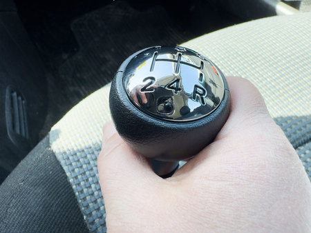 Hand gripping manual gear shift in car interior close-up.の写真素材