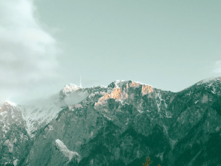 Sunrise on snow-capped mountain peaks against a clear sky.の写真素材
