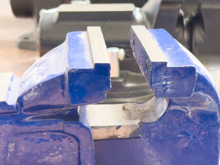 Close-up of blue metal vise on a workbench in a workshop setting.の写真素材
