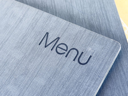 Textured grey menu cover with black lettering in restaurant setting.の写真素材