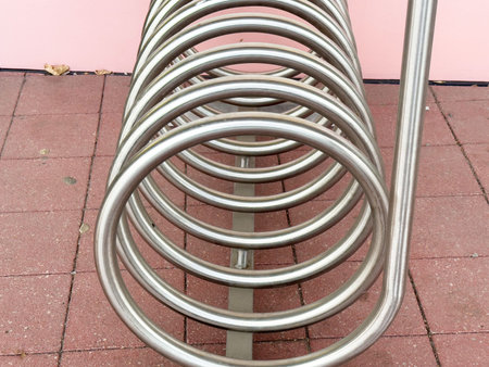 Curved metal bike rack with close-up circular design on brick pavement.