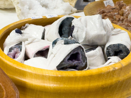Colorful mineral geodes displayed in wooden bowl at gemstone market.の写真素材