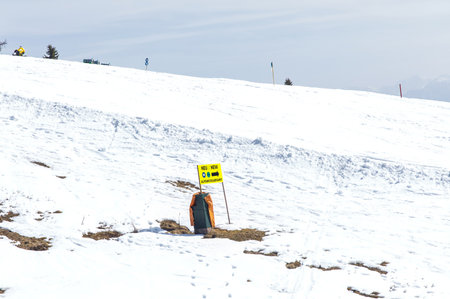 Sunny snowy landscape with safety sign on snow-covered hill.の写真素材
