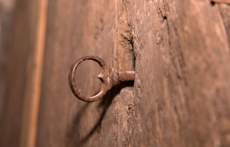 Rusty iron key in weathered wooden door lock with vintage texture.の写真素材