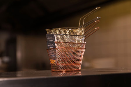Stacked mesh baskets in industrial kitchen setting with soft lighting.