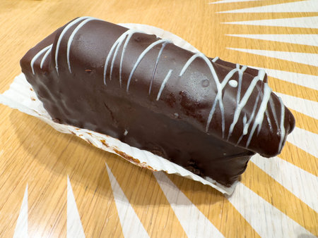 Chocolate-covered cake with white icing on wooden table.