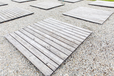 Wooden platforms on gravel surface in outdoor setting.