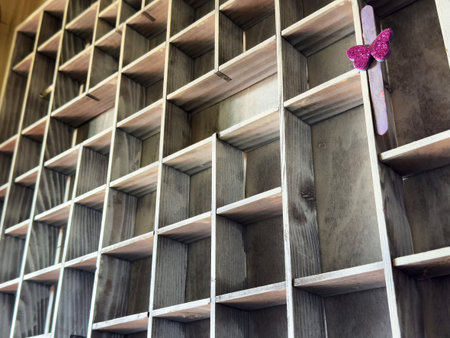 Empty wooden grid with a single decorative pink butterfly stick.