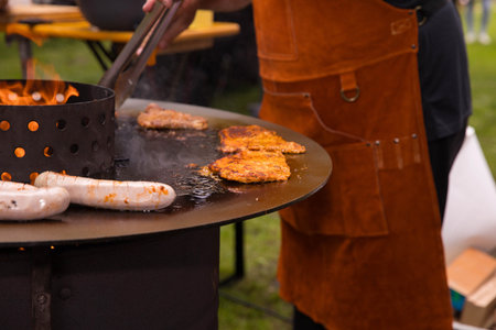 Outdoor barbecue with grilled meats and sausages on open flame.
