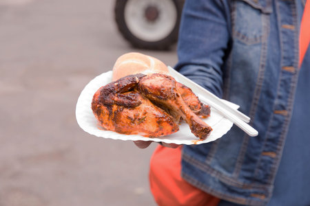 Bbq grilled chicken on paper plate with bread in outdoor setting.の写真素材