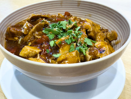 Delicious bowl of savory chicken stew garnished with fresh herbs.の写真素材