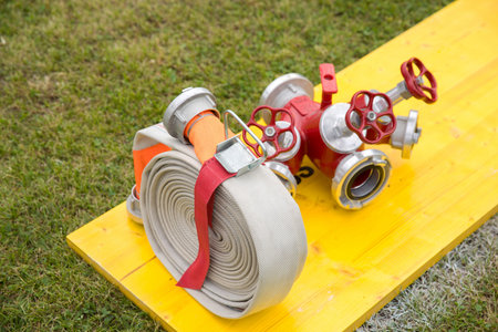 Fire hose and valves on yellow board in outdoor setting.