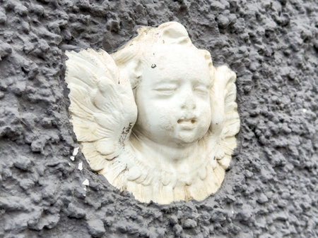 Cherub relief sculpture on textured wall.の写真素材