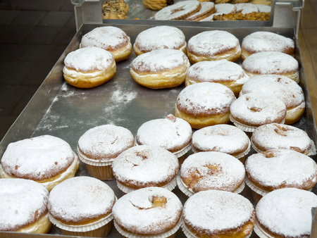 Tray of fresh powdered sugar donuts in bakery display.の写真素材
