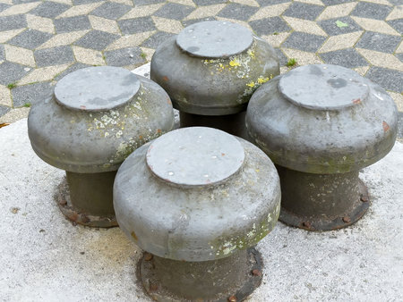 Rusty metal bollards on geometric patterned pavement with moss and lichen.の写真素材