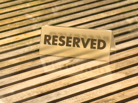 Reserved sign on wooden table with slatted pattern and glass reflection.の写真素材