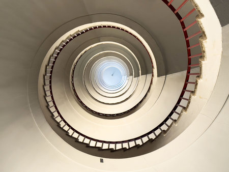 Abstract spiral staircase with minimalist design and red railings.