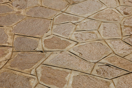 Stone pavement with irregular polygonal pattern and natural brown tones.の写真素材