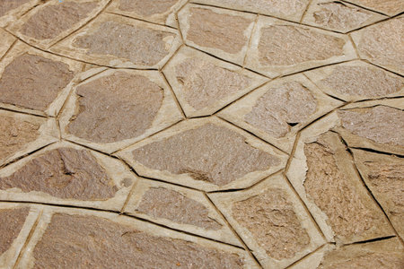 Textured stone pavement with irregular patterns and natural brown tones.